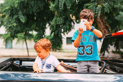 Boy and son while sitting on car outdoors