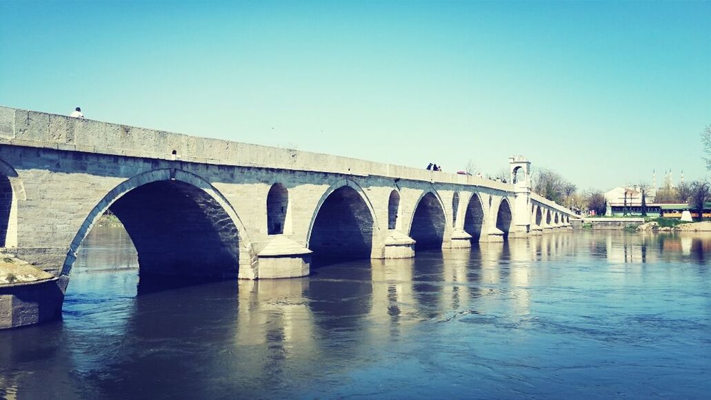 clear sky, architecture, built structure, water, connection, bridge - man made structure, arch, bridge, copy space, reflection, waterfront, river, building exterior, arch bridge, blue, outdoors, engineering, transportation, day, canal