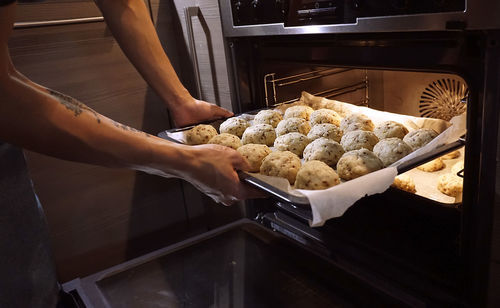 Cropped image of man putting tray into oven