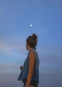 Rear view of woman standing against blue sky