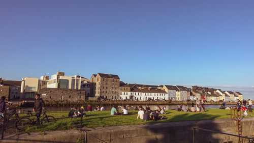 People on buildings against clear blue sky