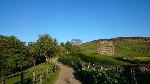 Walkway leading to built structure against clear blue sky