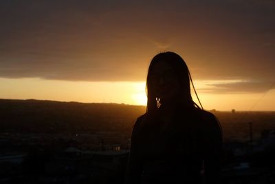 Portrait of silhouette woman standing against orange sky