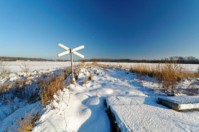 Snow covered field against clear blue sky