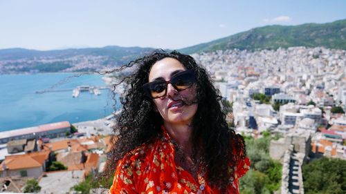 Portrait of woman wearing sunglasses against city