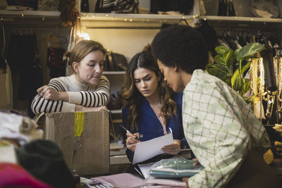 Multi-ethnic female colleagues discussing over document at boutique