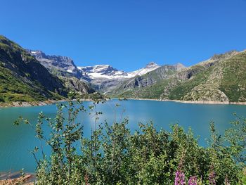 Scenic view of lake and mountains against clear blue sky