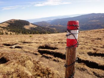 Red wooden post on field by mountains against sky / fence on the  border