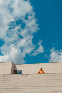 Low angle view of man sitting against building
