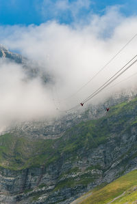 Overhead cable car over mountains against sky