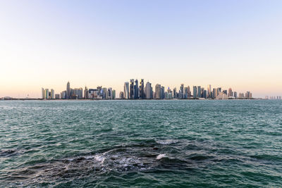 Sea and cityscape against clear sky