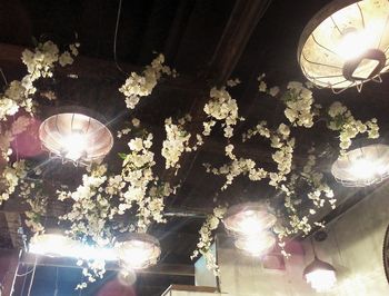 Low angle view of illuminated light bulb hanging from ceiling