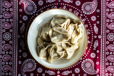 Georgian khinkali served in the bowl on traditional supra tablecloth covered with black pepper spice