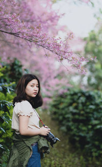 Full length of woman standing by flower tree