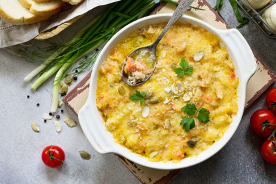 Homemade baked casserole crumble with red fish, white bread and cheese on the rustic kitchen table. 