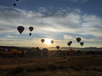 Hot air balloons on field against sky during sunset