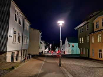 Illuminated street amidst buildings in city at night