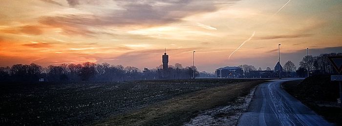 Road by city against sky during sunset