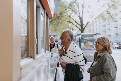 Smiling male and female senior friends shopping from store