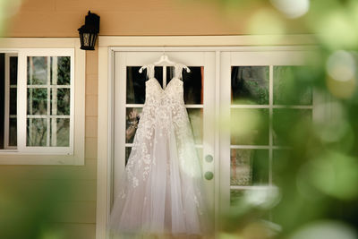 White lace wedding dress hanging on the dookr outside the house in the summer morning