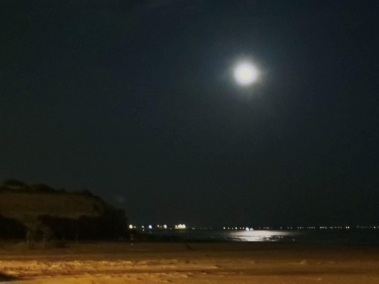 VIEW OF ILLUMINATED SEA AGAINST SKY AT NIGHT