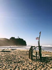 Scenic view of beach against clear sky. wooden sculpture with american flag