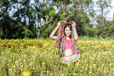 Portrait of young woman standing amidst marigold flowers on field