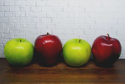 Close-up of apples on table against wall