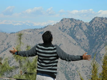 Rear view of man on mountain range against sky