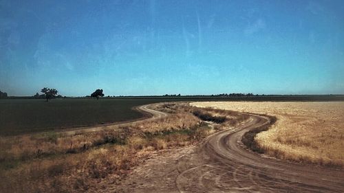 Dirt road passing through field