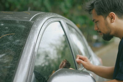 Side view of young man looking through car