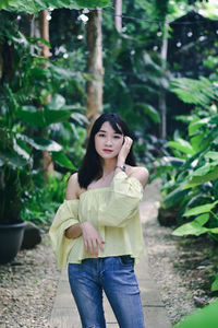 Portrait of beautiful young woman standing against plants