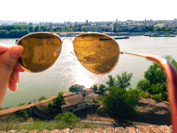 Close-up of hand holding cityscape against river