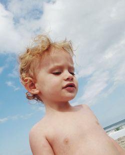 Portrait of shirtless boy looking away against sky