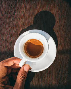 Cropped image of hand holding coffee cup on table