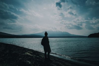 Rear view of man standing on sea against sky