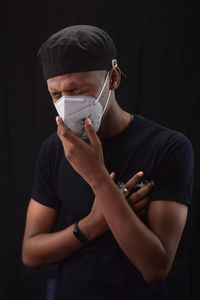 Midsection of man wearing hat standing against black background
