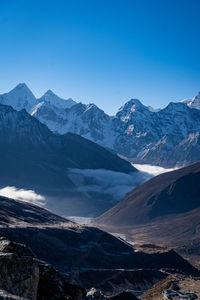 Scenic view of snowcapped mountains against clear blue sky