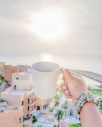 Woman holding coffee cup against sky