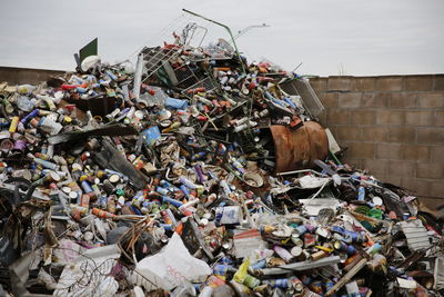 Stack of garbage by metal structure against sky