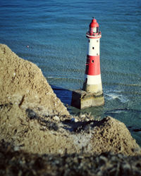 Lighthouse by sea against buildings