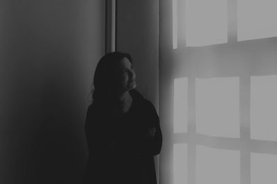 Thoughtful woman with arms crossed looking at wall