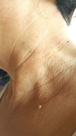 Close-up of shirtless man with woman in background