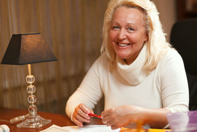 Portrait of smiling senior woman sitting at home