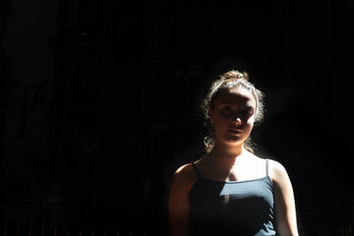 Portrait of young woman against black background