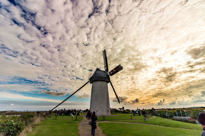Windmill on field against cloudy sky