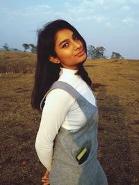 Portrait of woman standing on field against sky
