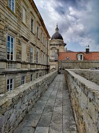 Footpath amidst buildings against sky in city