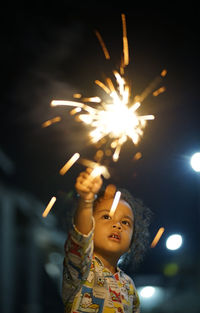 Low angle view of woman with fire crackers at night