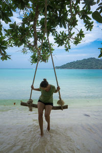 Rear view of boy on beach against sky